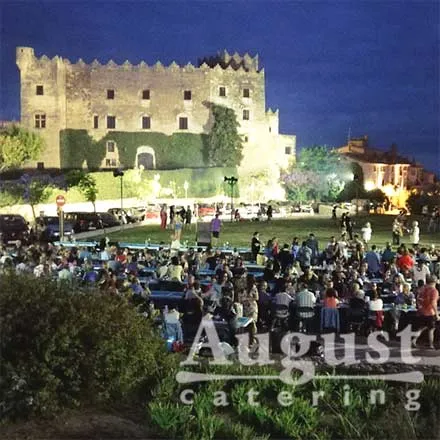 Sopar popular a la nit amb centenars de comensals davant d'un castell - August Càtering